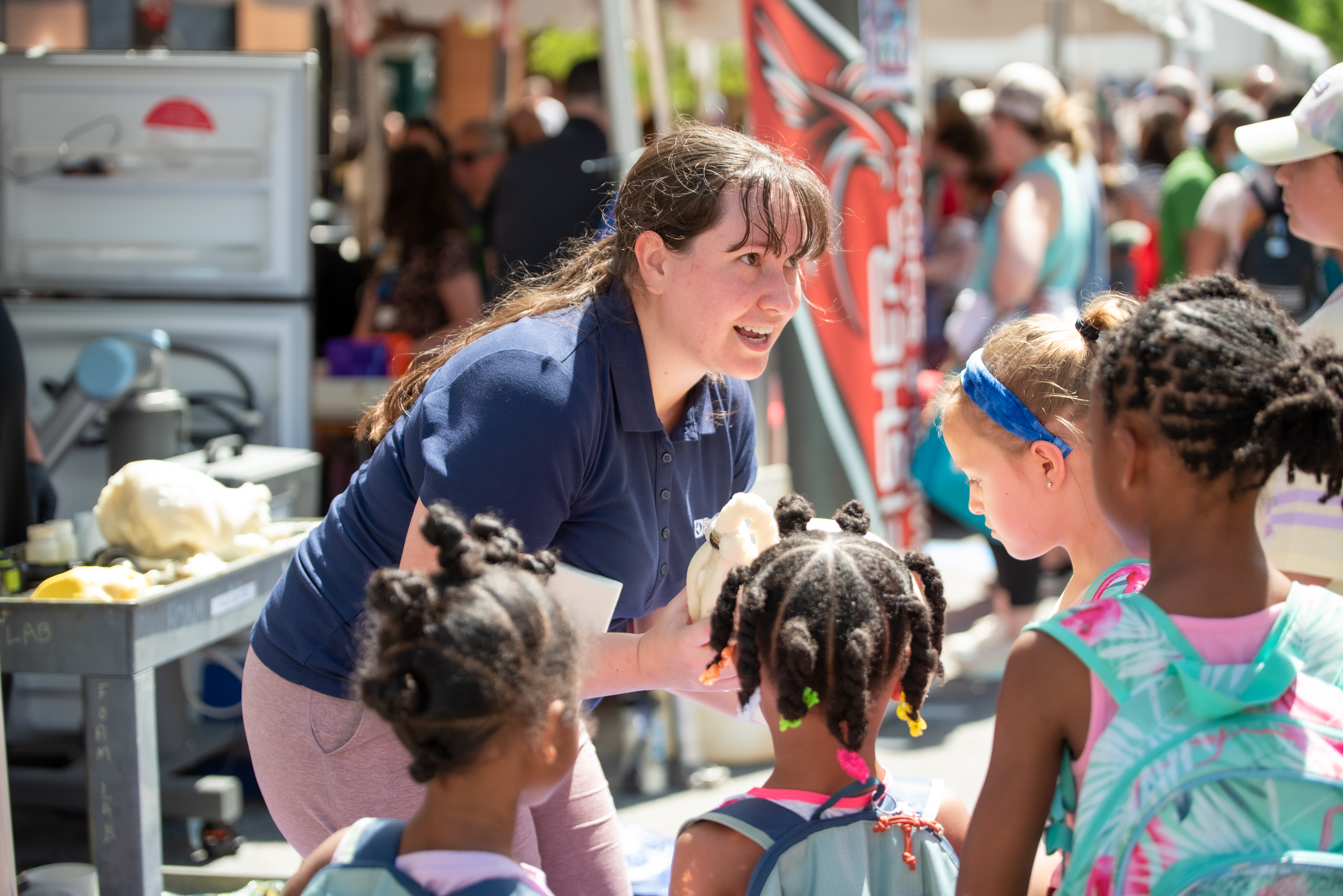 A woman speaking to children participating at an festival booth